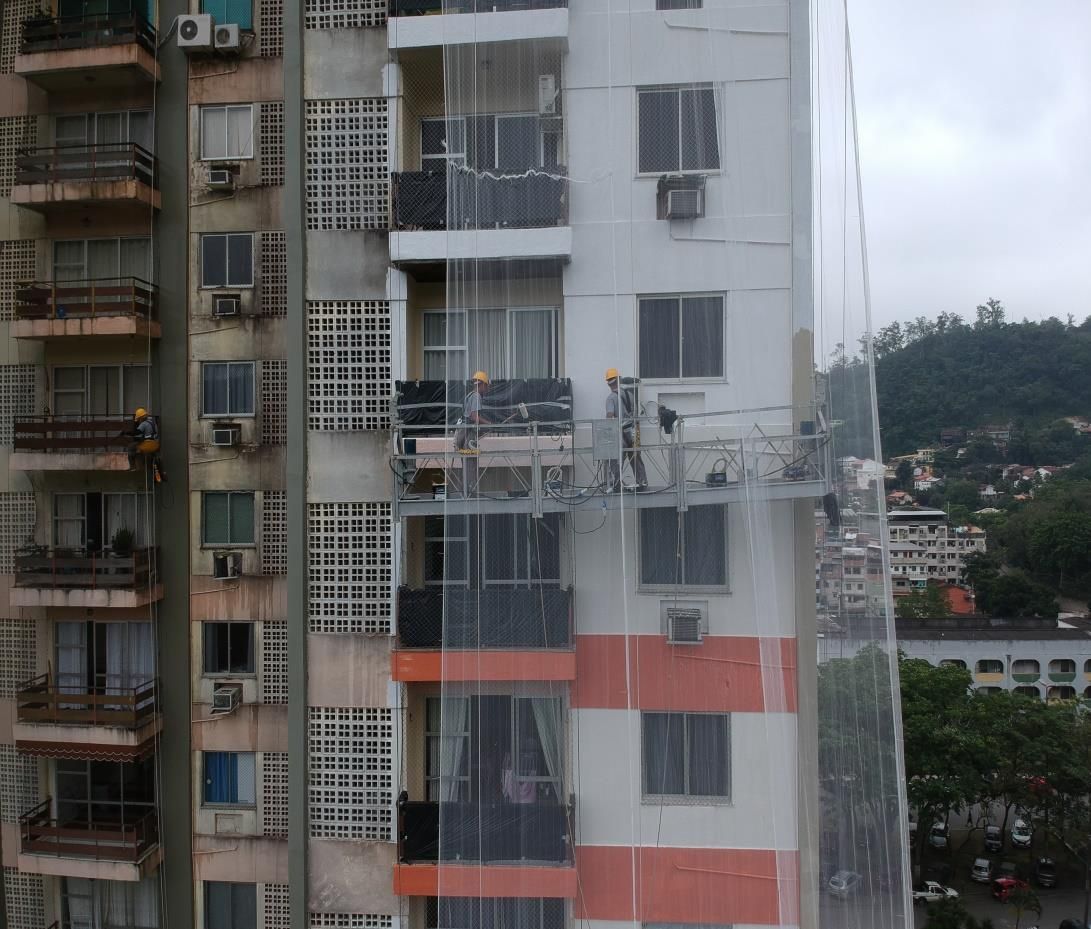 Fachada de condomínio residencial em reforma com balancim